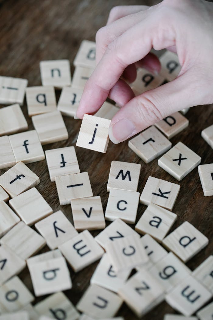 services-01 Hand arranging wooden alphabet tiles, representing learning and creativity.